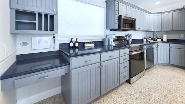 A modern kitchen with grey cabinetry, a stainless steel oven, and a microwave.