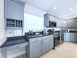 A modern kitchen with grey cabinetry, a stainless steel oven, and a microwave. - The Seaside Launch Pad in Cape Canaveral - NEW (Cape Canaveral)
