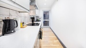 Eine moderne Küche mit weißen Schränken, einem schwarzen Wasserkocher und einer Holzausziehtafel.
