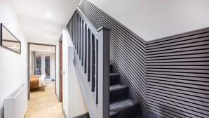 Eine moderne Treppe mit dunkler Geländer und Wandverkleidung aus Lamellen.
