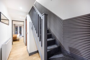 Una escalera moderna con barandilla oscura y un diseño de pared con listones.