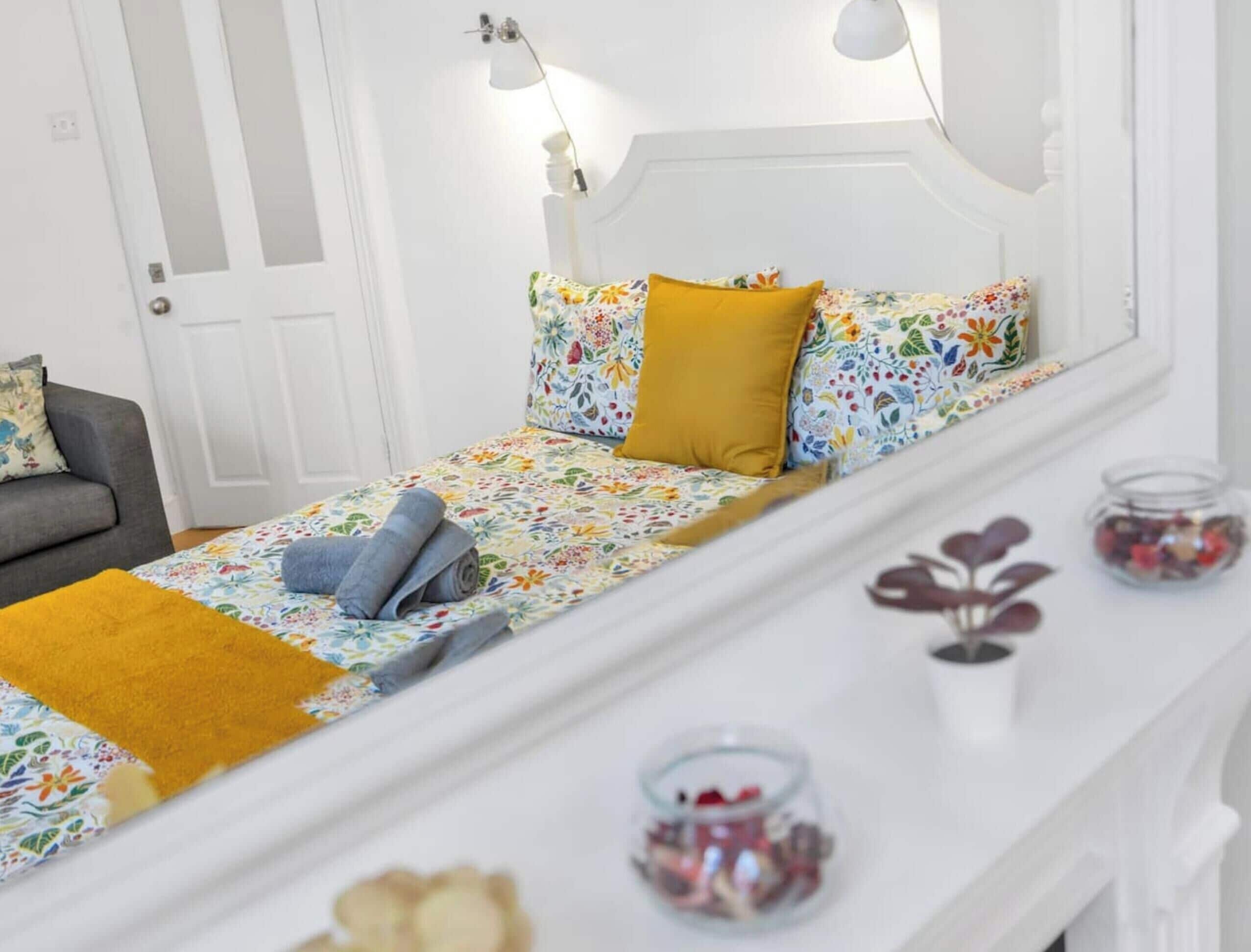 A bedroom with a bed, a nightstand, a lamp, and a mirror.