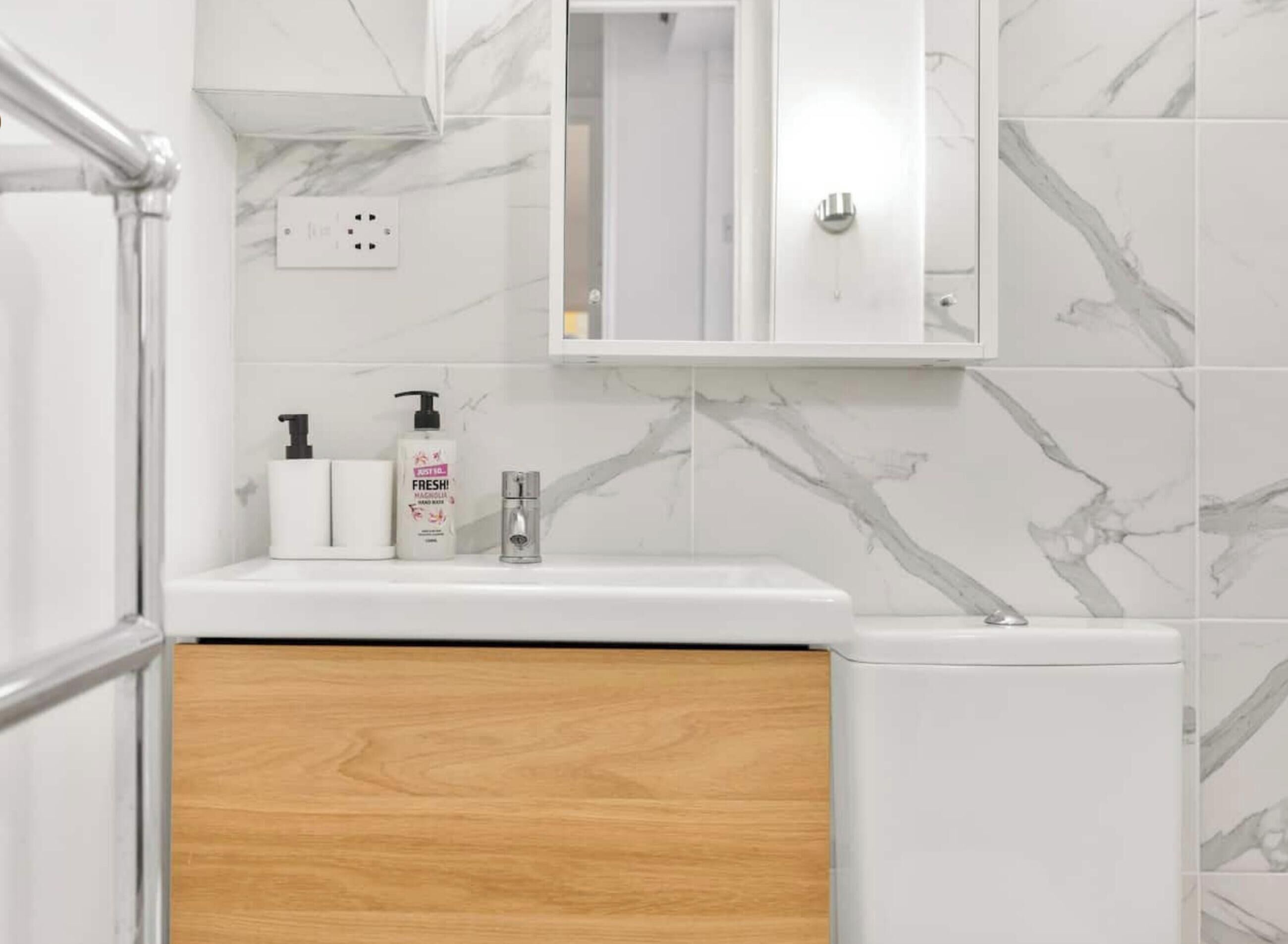 A bathroom with a white sink, a mirror above it, and a marble-patterned wall.