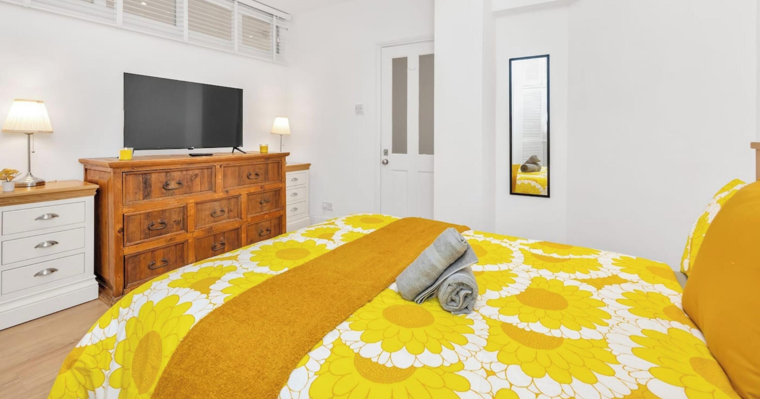 A bedroom with a bed, a dresser, a television, and a door.