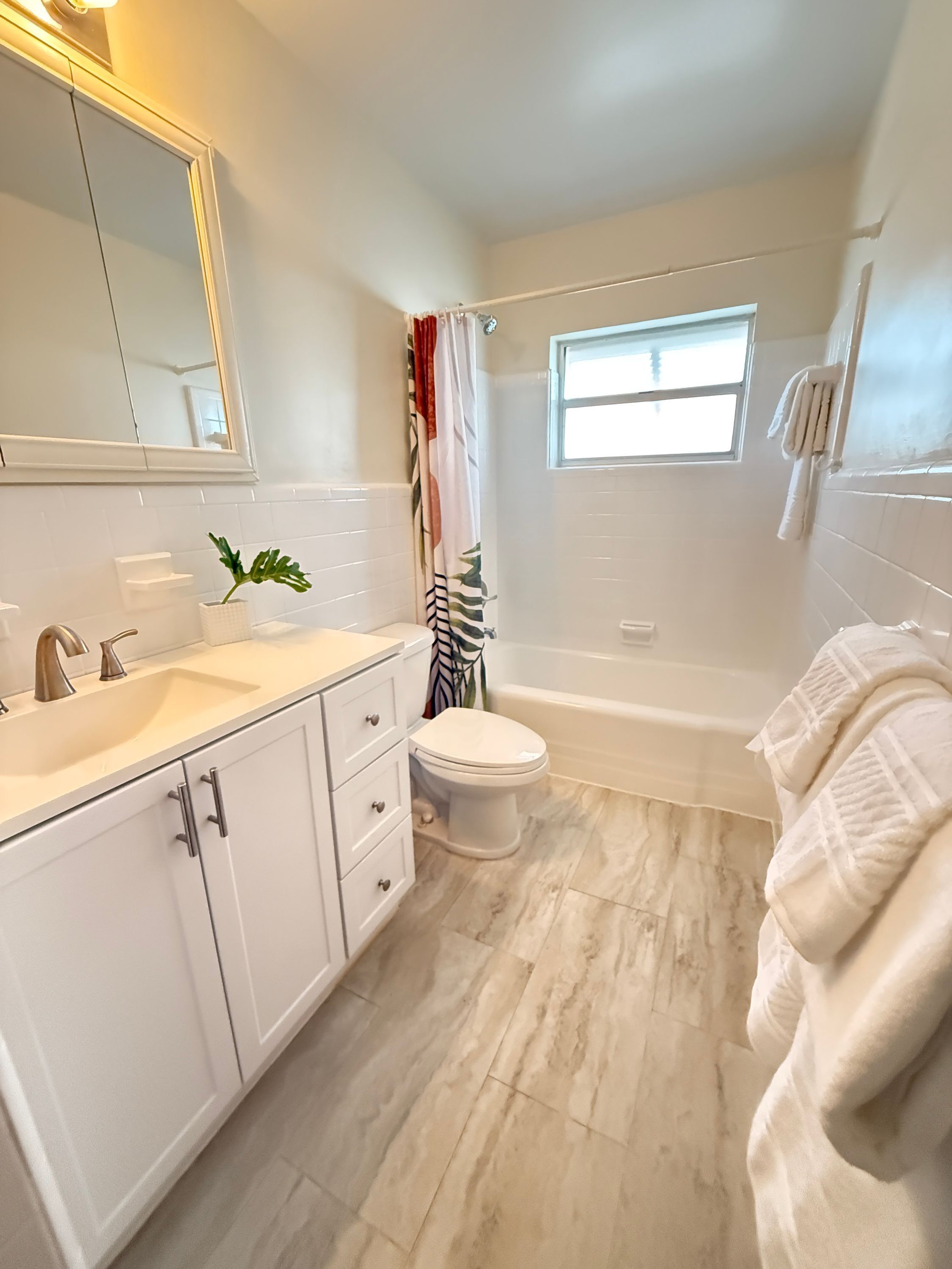 A modern bathroom with a white vanity, a toilet, and a bathtub.