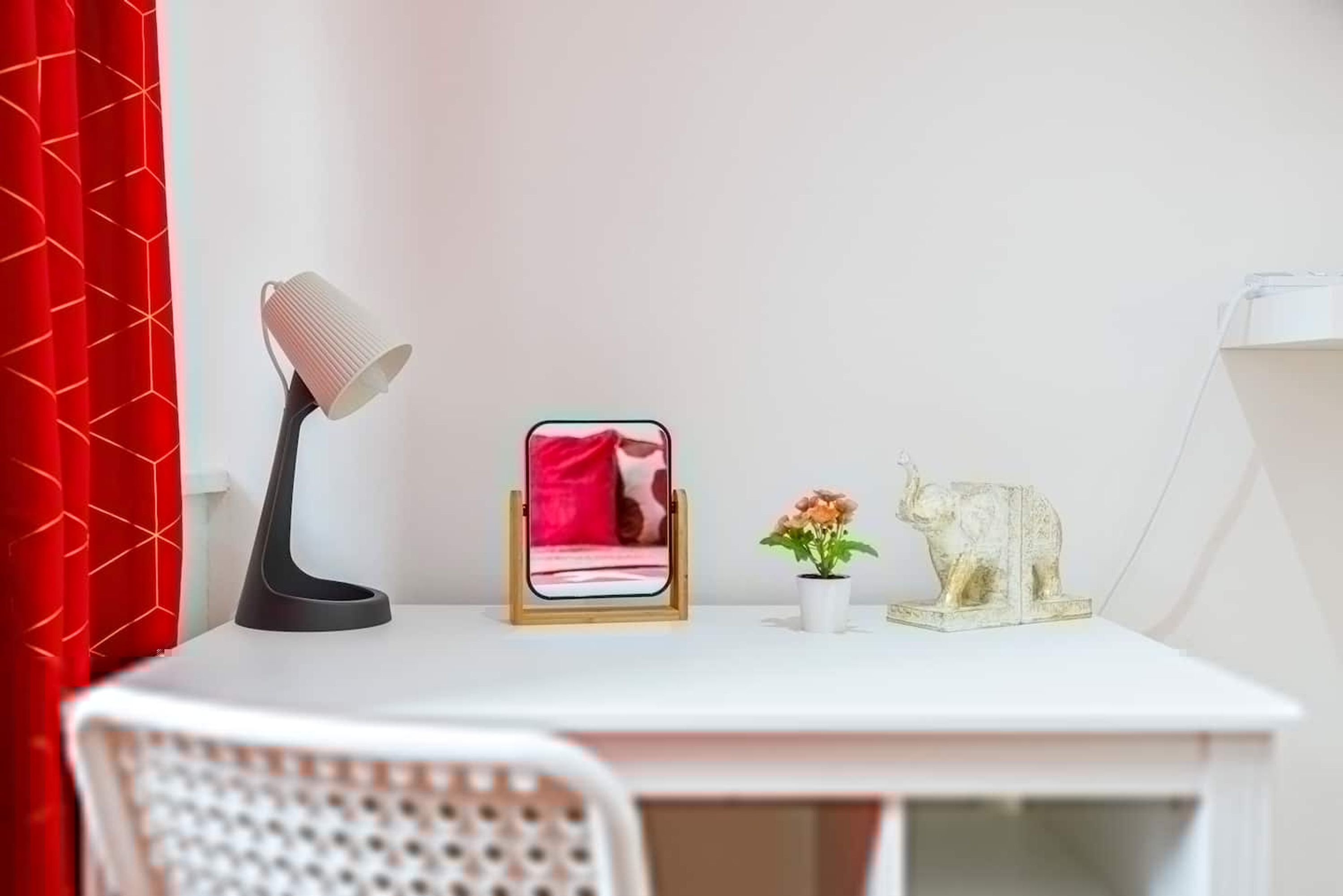 A white desk with a lamp, a framed photo, a small plant, and a decorative elephant figurine.