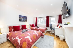 A modern bedroom with two beds, a desk, a chair, a TV, and a window with curtains. - 2 Bedroom Charming Magnificent Flat (London)