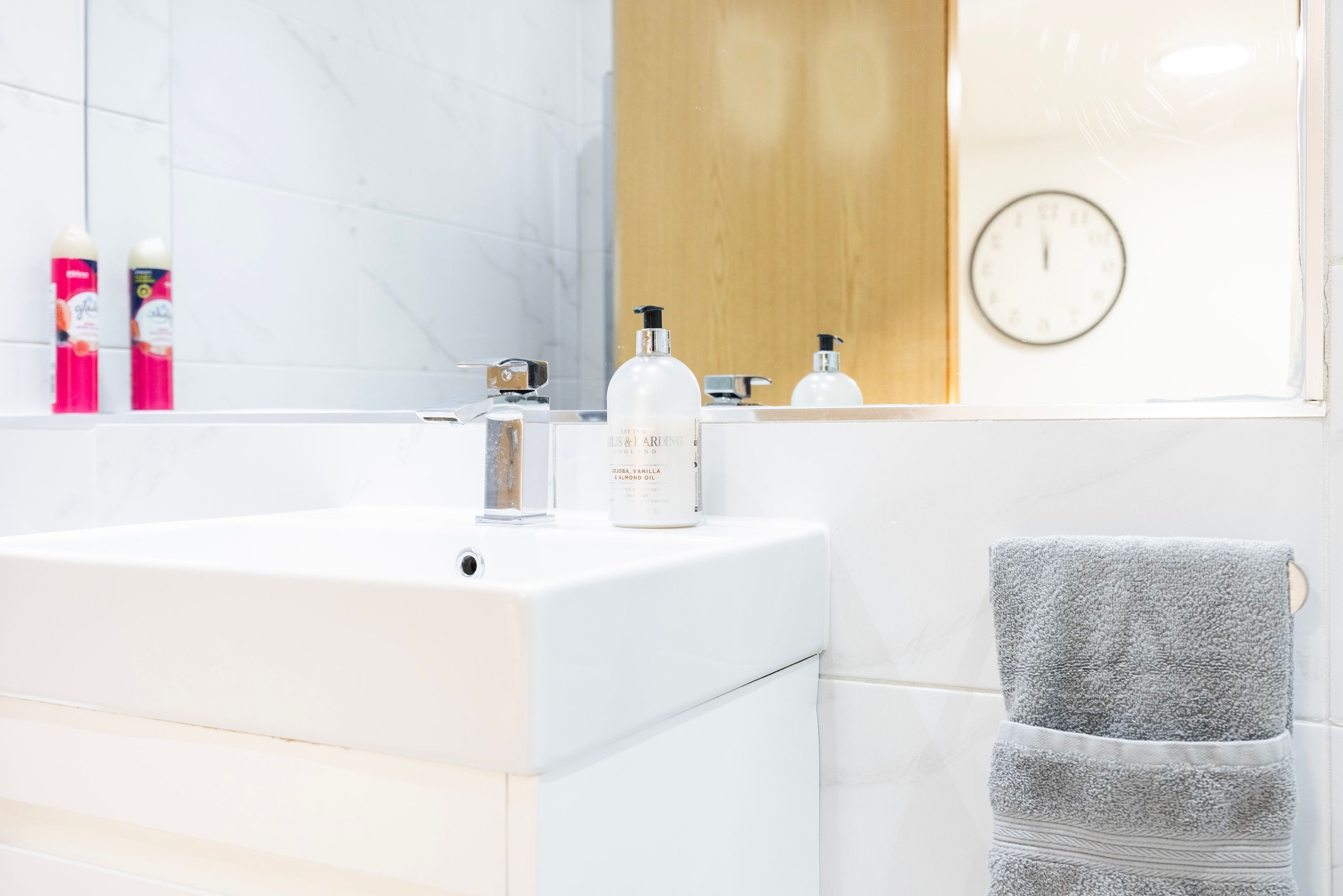 A bathroom with a white sink, a mirror, and toiletries.
