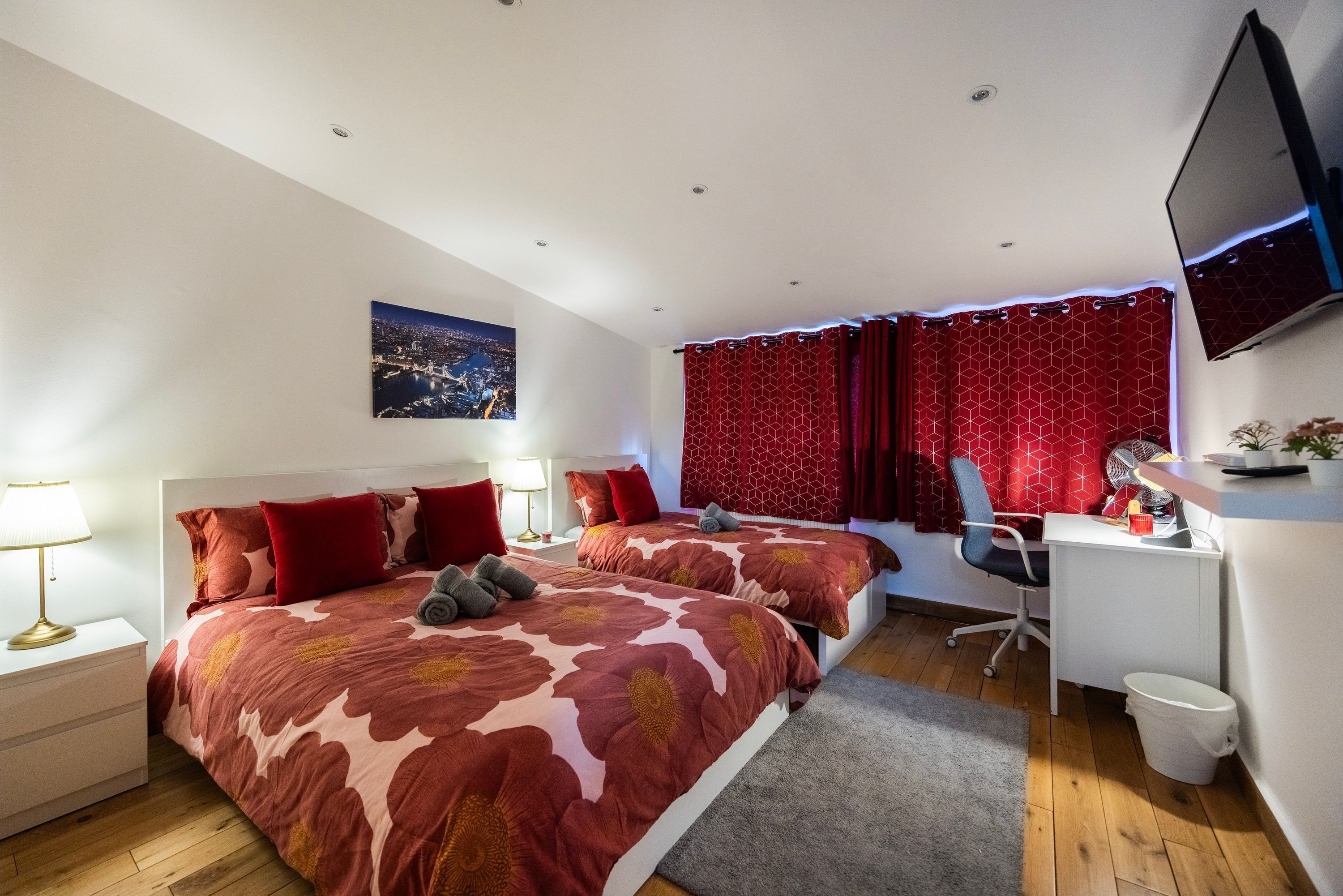 Une chambre avec deux lits, un bureau, une chaise, une télévision et une table de chevet avec une lampe.