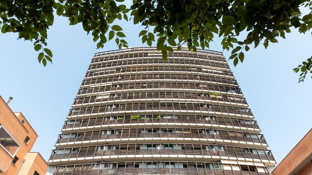 Een meerlaags gebouw met een modern architectuurontwerp, met balkons op elke verdieping en een heldere lucht op de achtergrond.