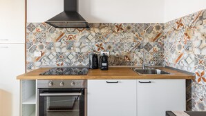 Een keuken met een houten aanrecht, een roestvrijstalen spoelbak en een zwarte afzuigkap, plus een achterwand met een patroon.