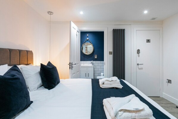 A hotel room with a bed, a bathroom with a sink and mirror, and a door. - Harbourside Roof Terrace sea Views By Adliv (Ramsgate)