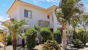 Une maison moderne à deux étages, dotée d’une façade en pierre et d’un toit recouvert de tuiles.