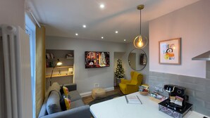 A modern living room with a sofa, a coffee machine, a TV, and a Christmas tree. - Old Town Trinity Apt No 3 By Adliv (Margate)