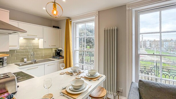 A modern kitchen with a dining area, large windows, and a view of the city. - Old Town Trinity Apt No 3 By Adliv (Margate)