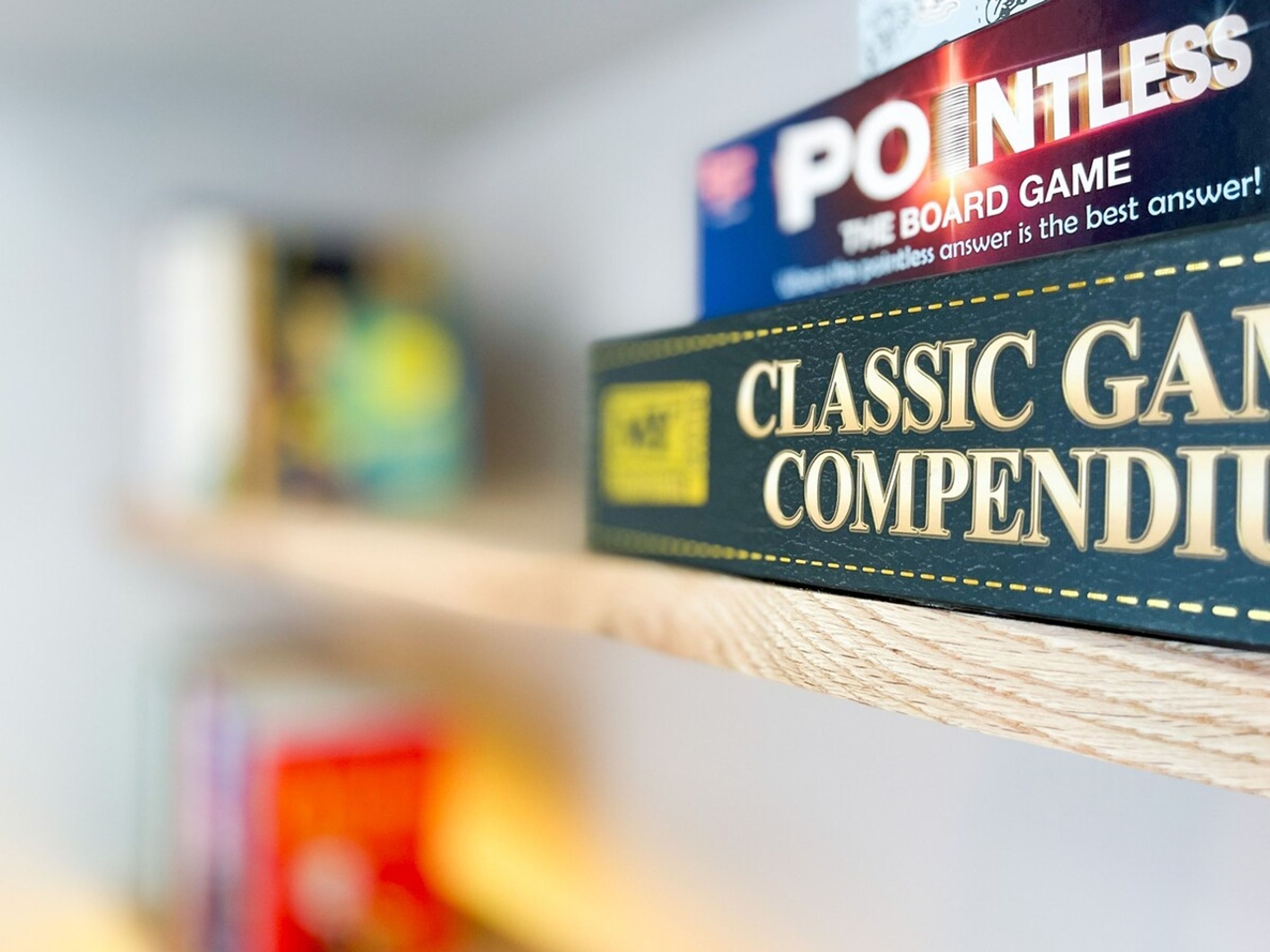 Um close-up de um jogo de tabuleiro intitulado 'POINTLESS' numa estante.