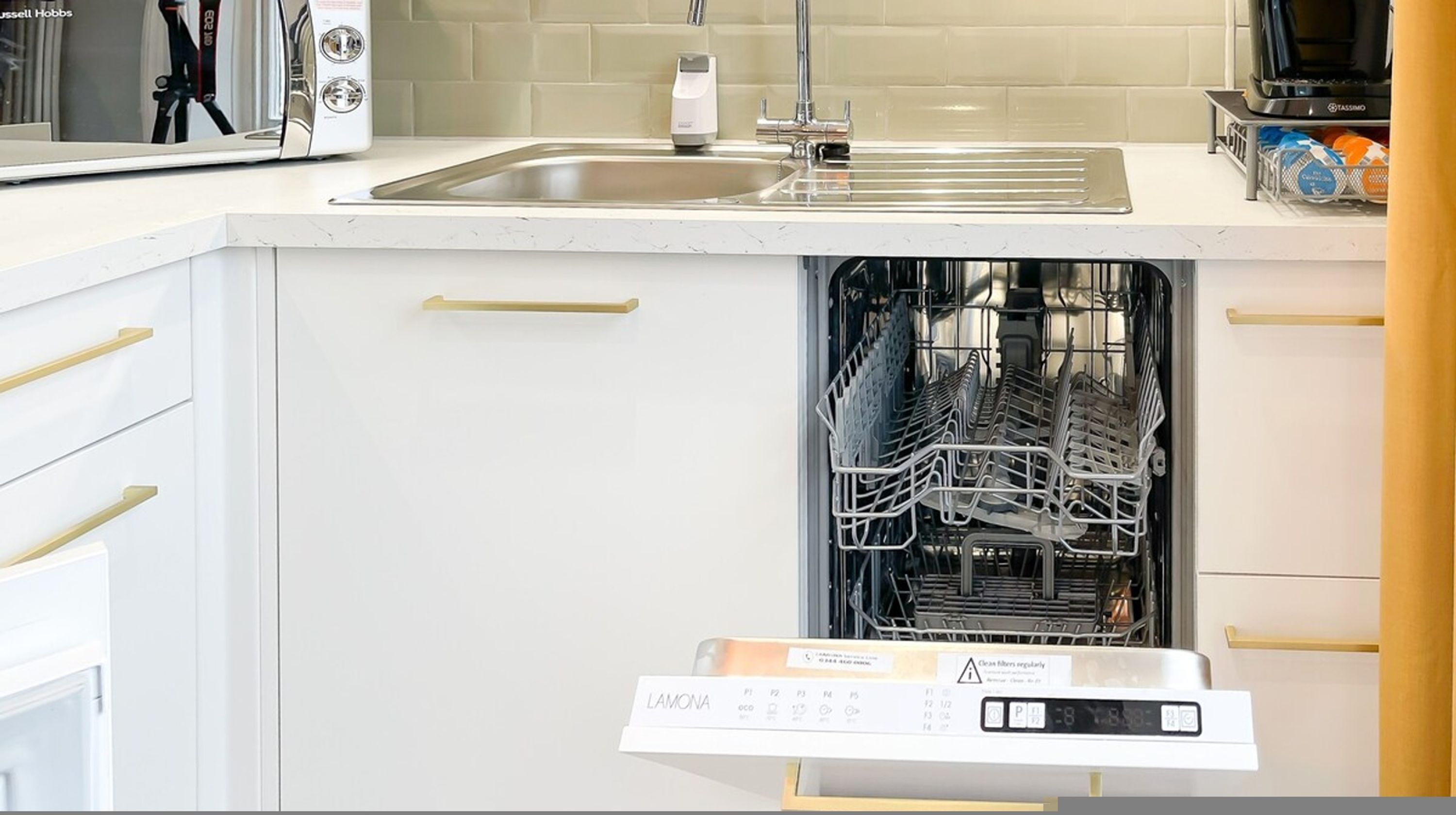 A kitchen with a dishwasher, a sink, and a coffee maker.