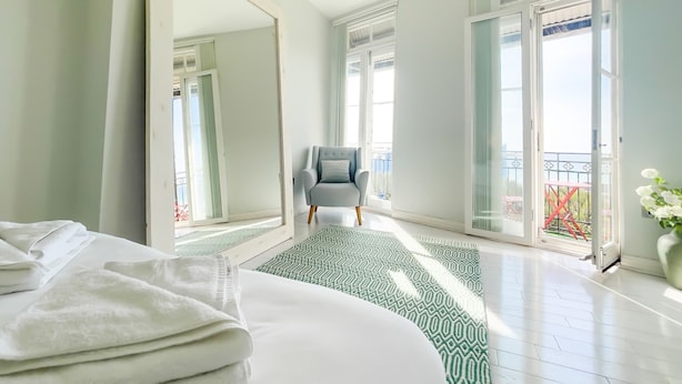 A hotel room with a large bed, a grey armchair, and a balcony with a view. - Seaview Apt Turner Contemporary Margate By Adliv (Margate)
