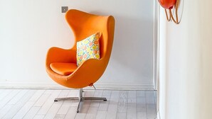 A room with a modern orange chair, a large illuminated sign reading "MARGATE," and a red fire extinguisher on the wall. - Seaview Apt Turner Contemporary Margate By Adliv (Margate)
