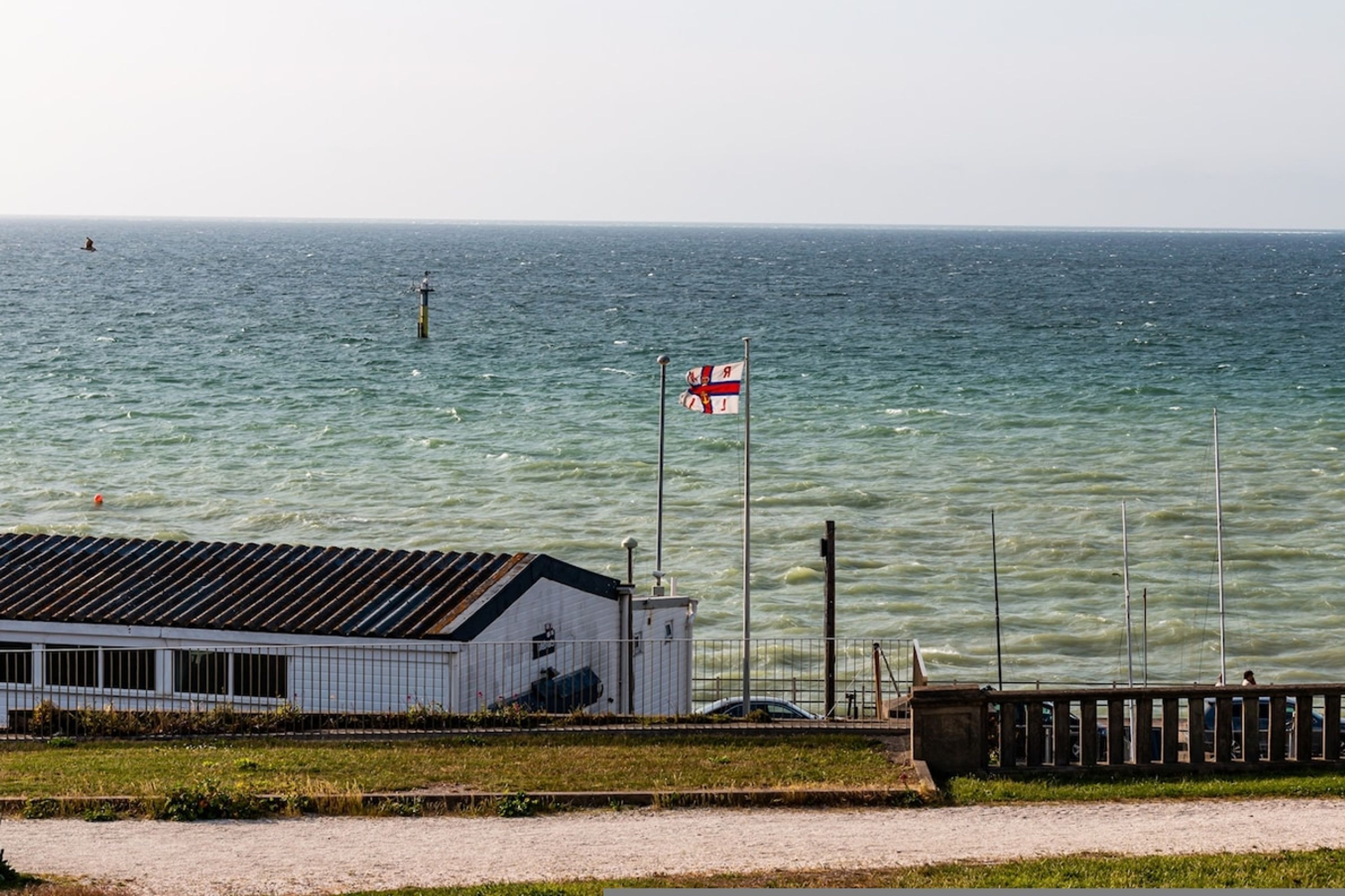 A coastal building with a flag, a pier, and a body of water.