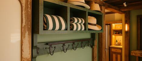 A wall-mounted hat rack with various hats and a shelf above it holding hats.