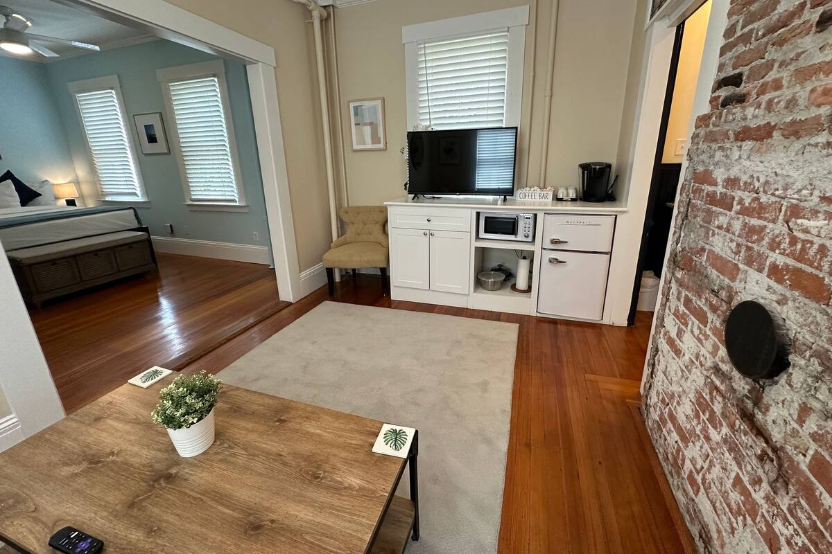 A modern kitchen with white cabinetry, a microwave, a coffee maker, and a television.
