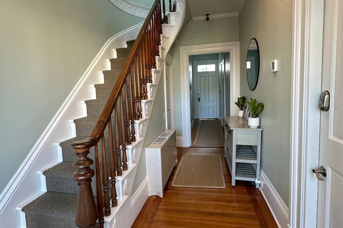A wooden staircase with a white railing leading to a landing.