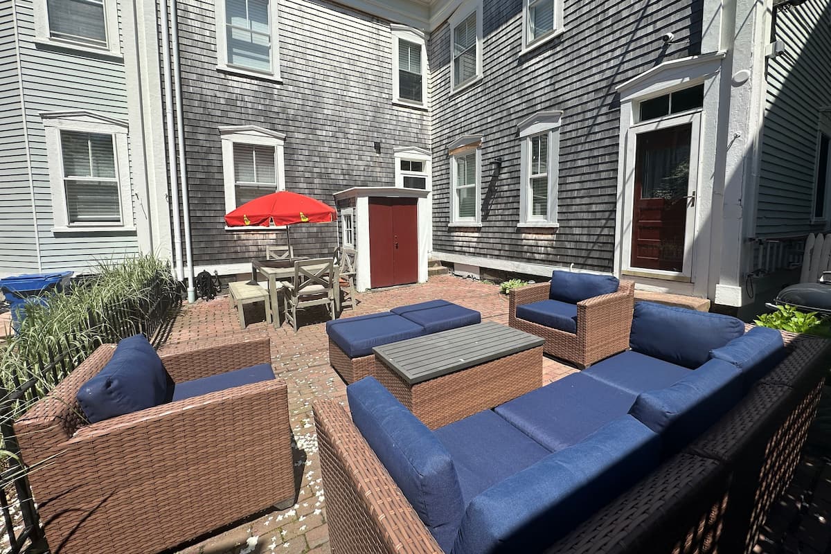 Eine Terrasse mit Korbmöbeln und einem roten Sonnenschirm.