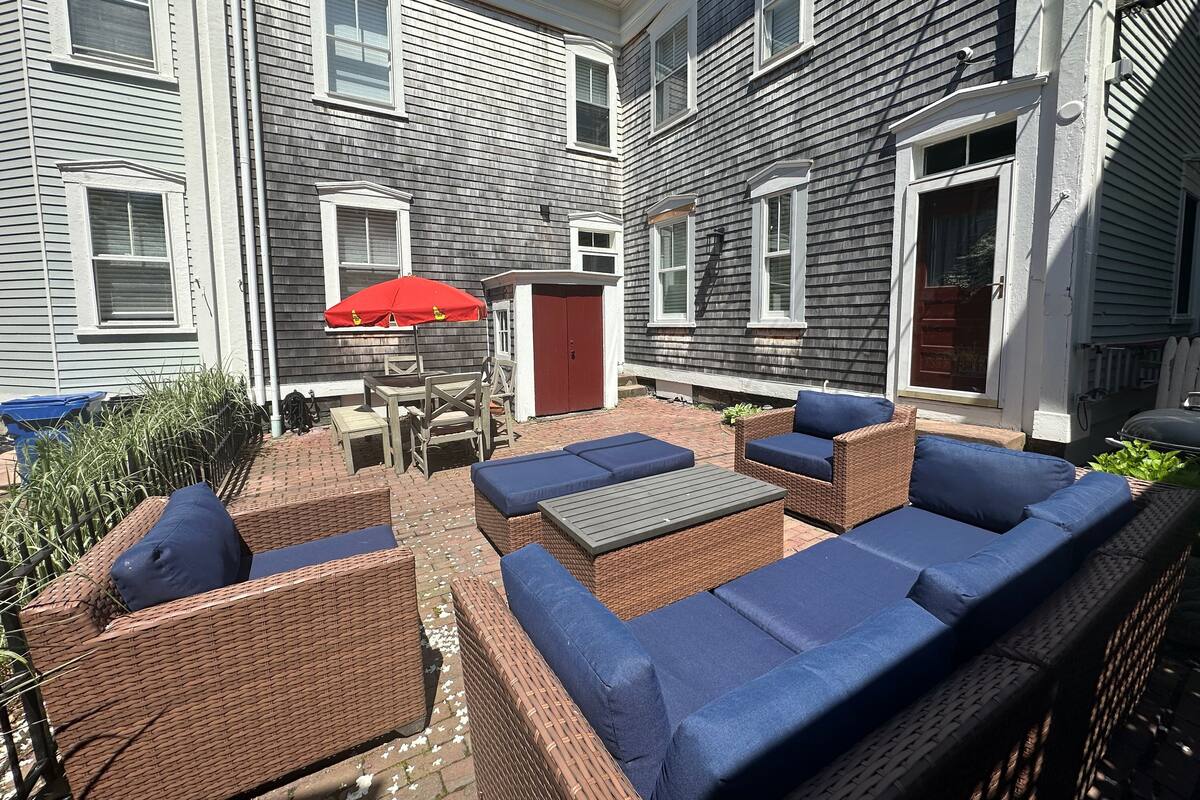 A patio area with wicker furniture and a red umbrella.