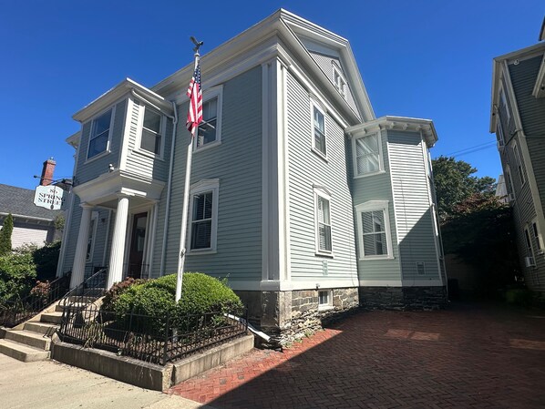 A two-story house with a brick driveway and a flagpole.