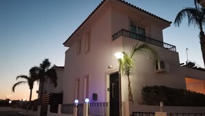 A two-story building with a balcony, a door with a number, and a small garden area. - Amelia Villa With Private Pool Wifi BBQ (Paralimni)