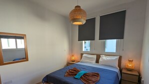 A bedroom with a bed, two bedside lamps, a hanging light, a mirror, and a window with a view. - Amelia Villa With Private Pool Wifi BBQ (Paralimni)