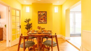 A dining area with a round table, chairs, and a painting on the wall.