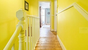 A hallway with yellow walls and wooden flooring, leading to a door at the end.