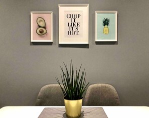 Ein Essbereich mit Tisch, Stühlen und drei gerahmten Kunstwerken an der Wand.