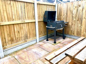 Un barbecue dans un jardin, avec une clôture en bois et une table de pique-nique.