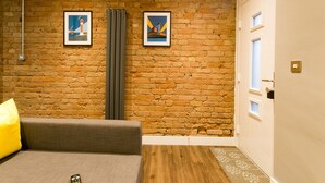 Ein Zimmer mit Ziegelwand, Heizkörper, Tür und einer Couch mit Kissen.