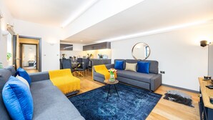 A modern living room with a grey sofa, blue pillows, a yellow throw, and a blue rug. - 2 Bed 2 Bath Deluxe Flat in Kensington (London)