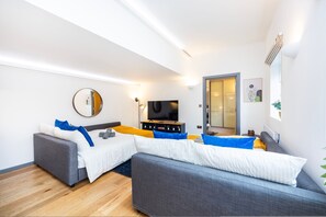 Una sala de estar moderna con un sofá, un televisor y un espejo.