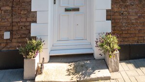 A white door with a decorative arch above it, flanked by two wall-mounted lanterns. - Dreamland Cottage Margate by Adliv (Margate)
