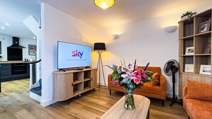 A modern living room with a flat-screen TV, a wooden coffee table, a sofa, and a floor lamp. - Dreamland Cottage Margate by Adliv (Margate)
