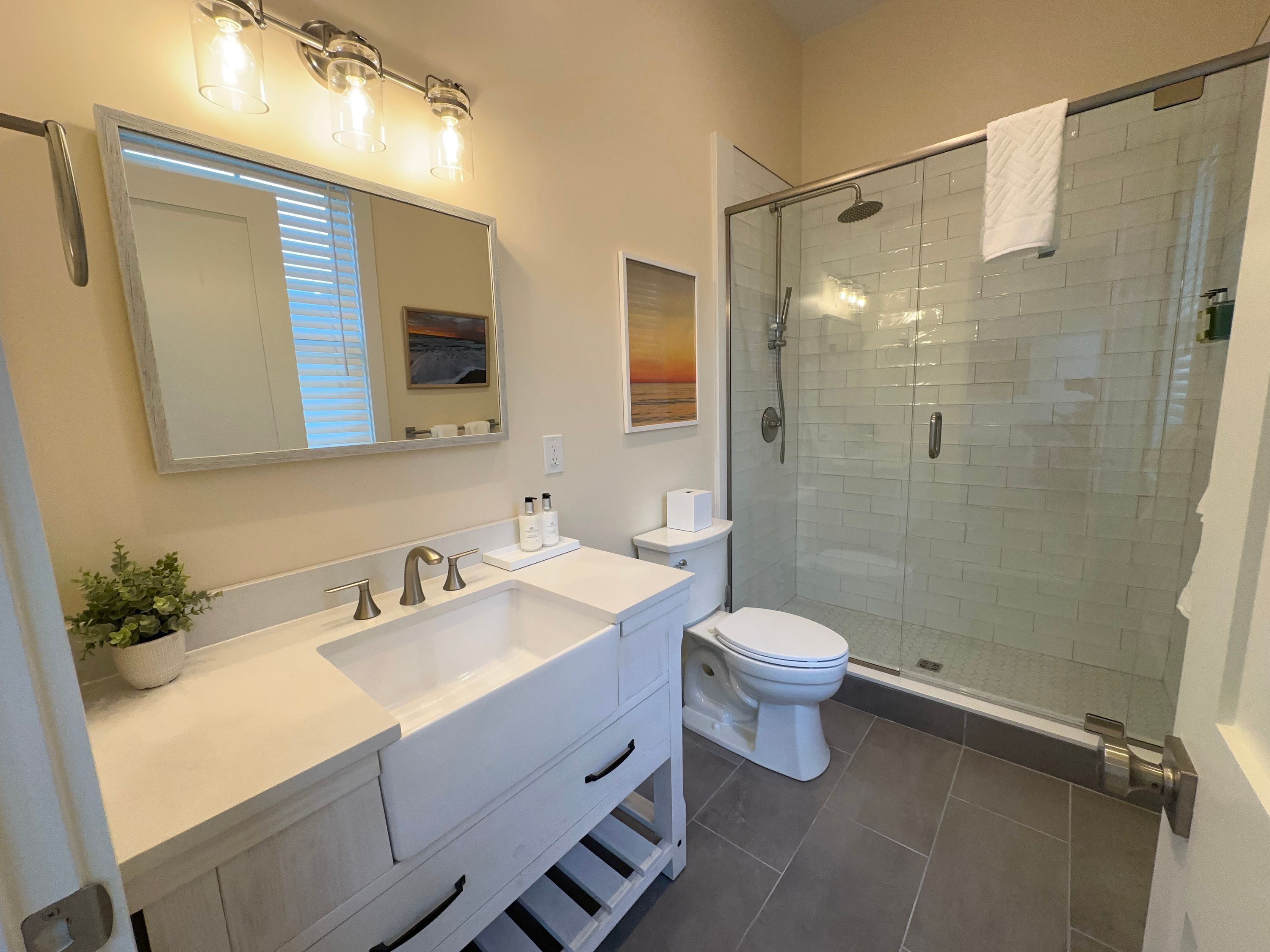 A modern bathroom with a glass-enclosed shower, a white sink with a mirror above, and a toilet.