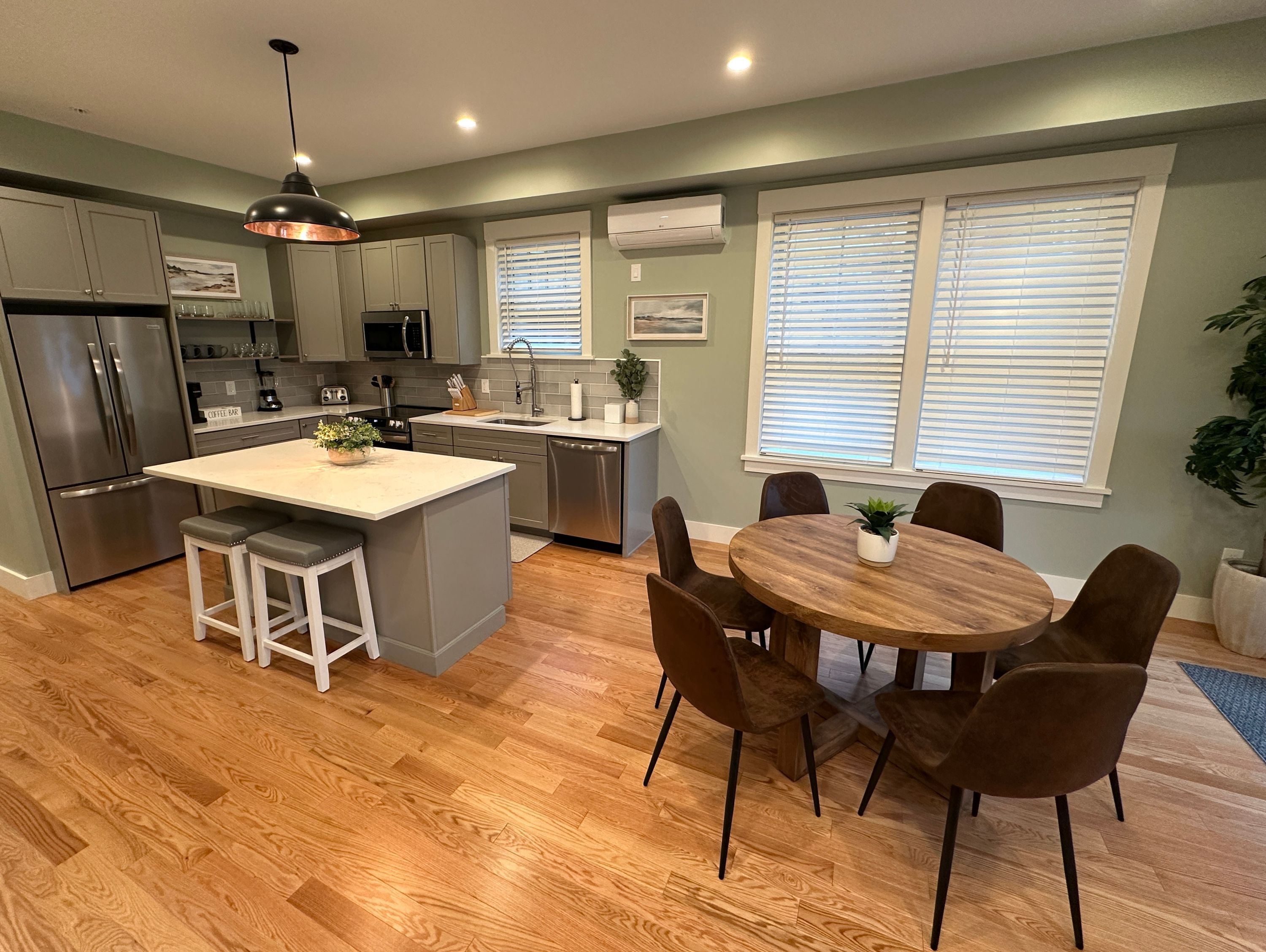 A modern kitchen with a central island, stainless steel appliances, and a dining area with a wooden table and chairs.
