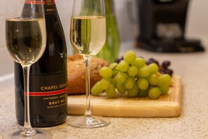 A bottle of Chapel Down Brut NV wine, two wine glasses, a loaf of bread, and a bunch of grapes on a wooden board. - Stylish Margate Coastal Home Parking By Adliv (Margate)