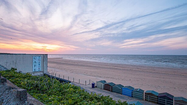 A beach with a concrete structure labeled "CAF" and a fence with small buildings. - Stylish Margate Coastal Home Parking By Adliv (Margate)