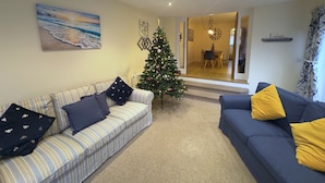 A living room with a striped sofa, a blue sofa, a Christmas tree, and a painting on the wall. - Stylish Margate Coastal Home Parking By Adliv (Margate)