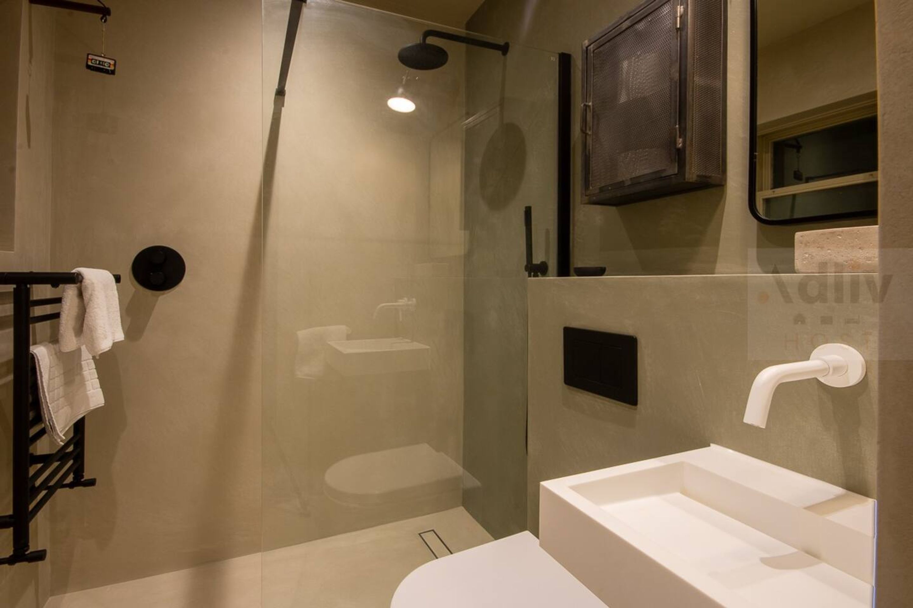Een moderne badkamer met een douchecabine van glas, een witte wastafel en een handdoekhouder.