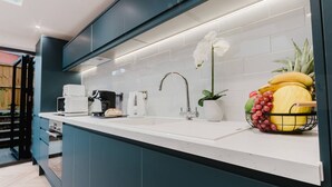 A modern kitchen with a white countertop, dark cabinets, and a sink. There is a coffee maker, a toaster, and a potted plant on the counter. - Luxury Seaside Home Parking Sleeps 8 by Adliv (Margate)
