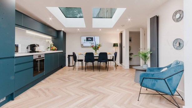 A modern kitchen with a dining area, skylights, and a blue chair. - Luxury Seaside Home Parking Sleeps 8 by Adliv (Margate)