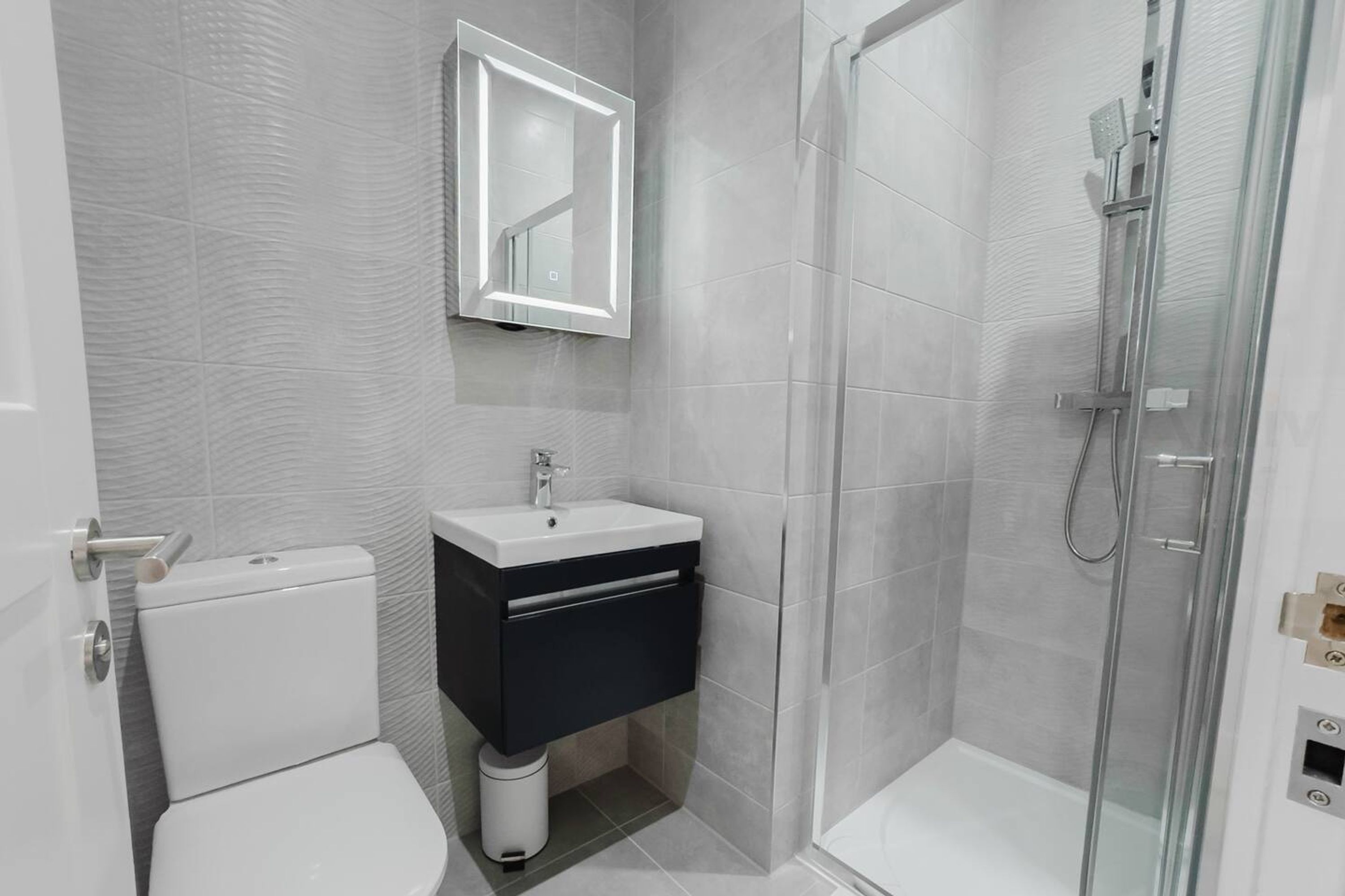 A modern bathroom with a toilet, sink, and glass-enclosed shower.